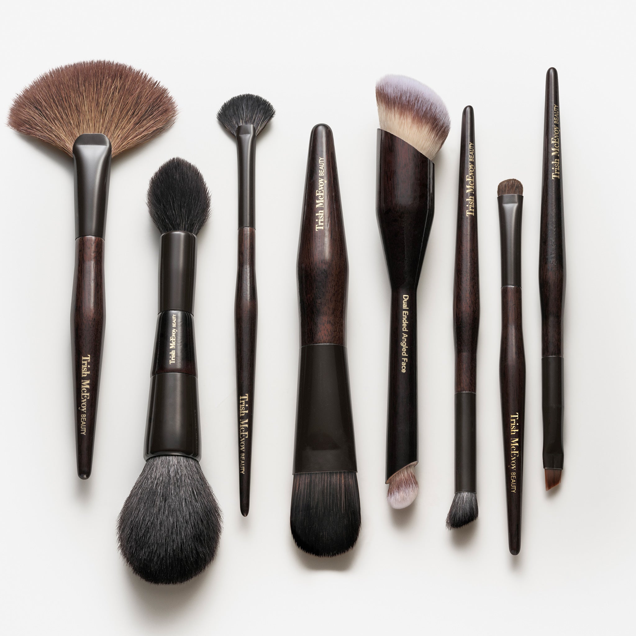 Set of makeup brushes with brown handles and various bristle types on a white background