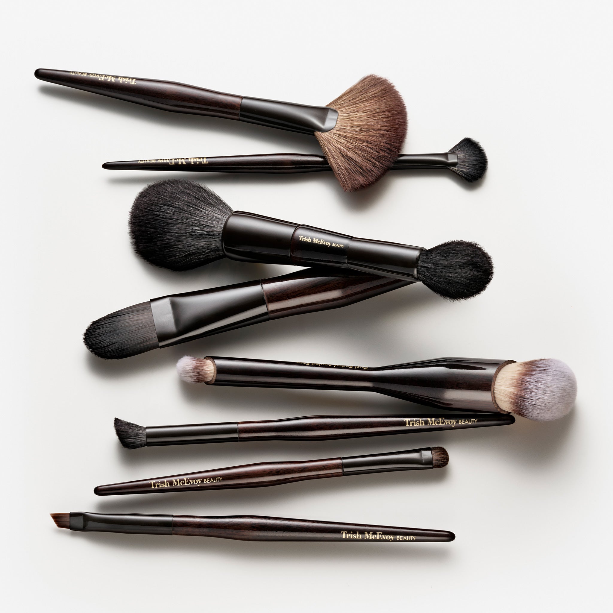Set of makeup brushes with brown handles and bristles on a white background