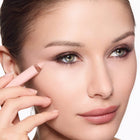 Close-up of a woman applying eye brightening pencil to her face.