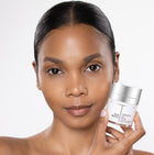 Woman holding a skincare product with a plain background
