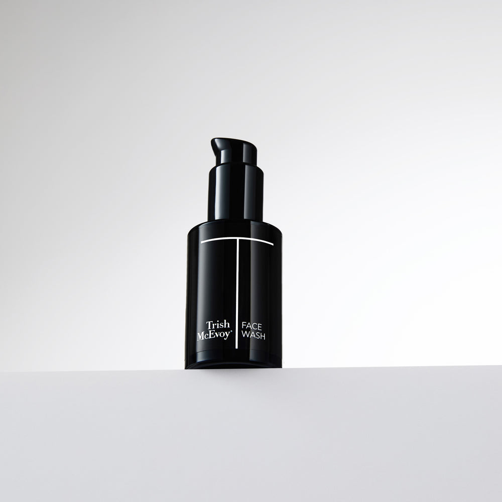 Black bottle of Trish McEvoy Face Wash on a light gray background