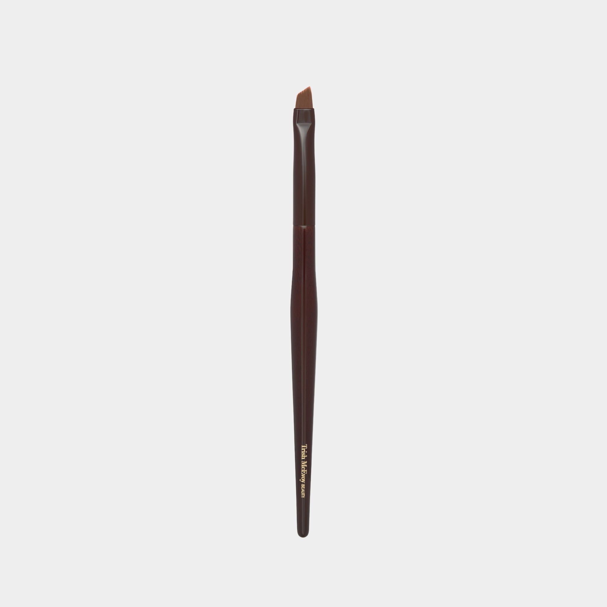 Makeup brush with brown handle and black bristle head on a light gray background