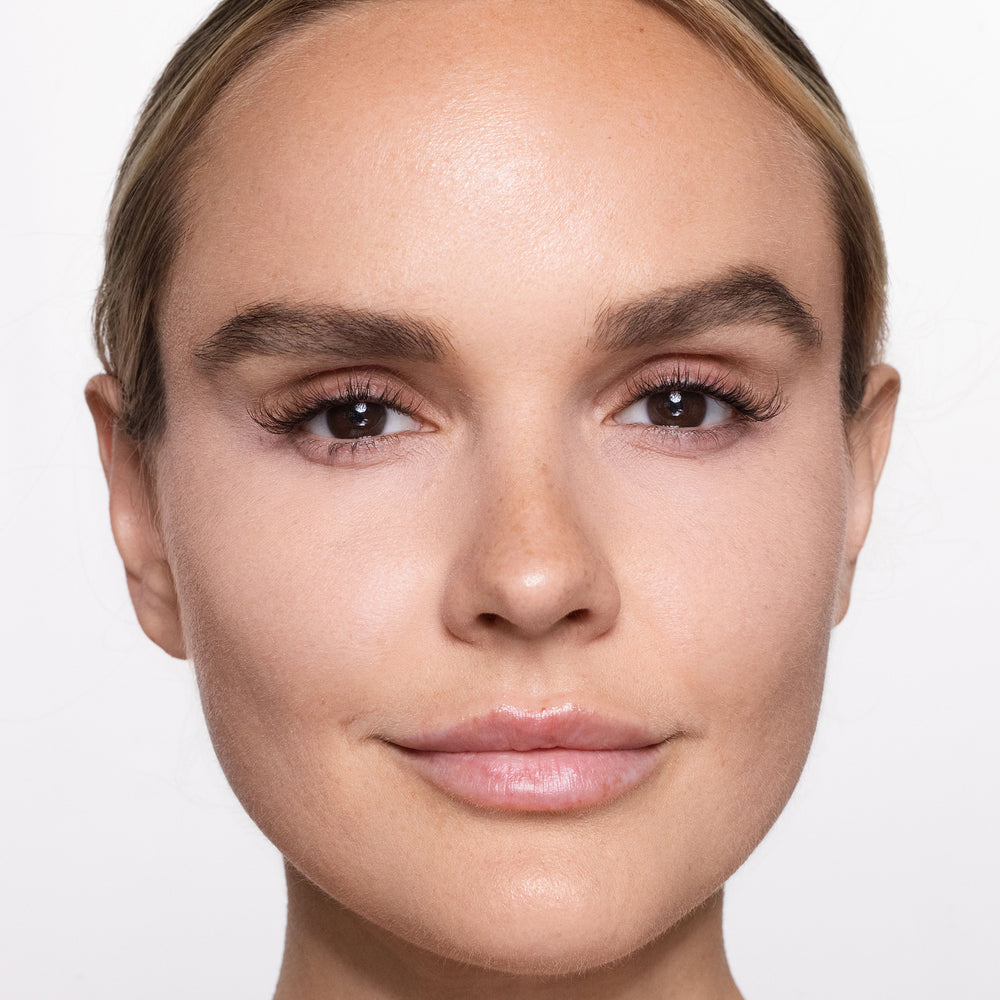 Close-up of a woman's face with a neutral expression on a light background