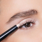 Close-up of an eye applying color white peach eyeliner.