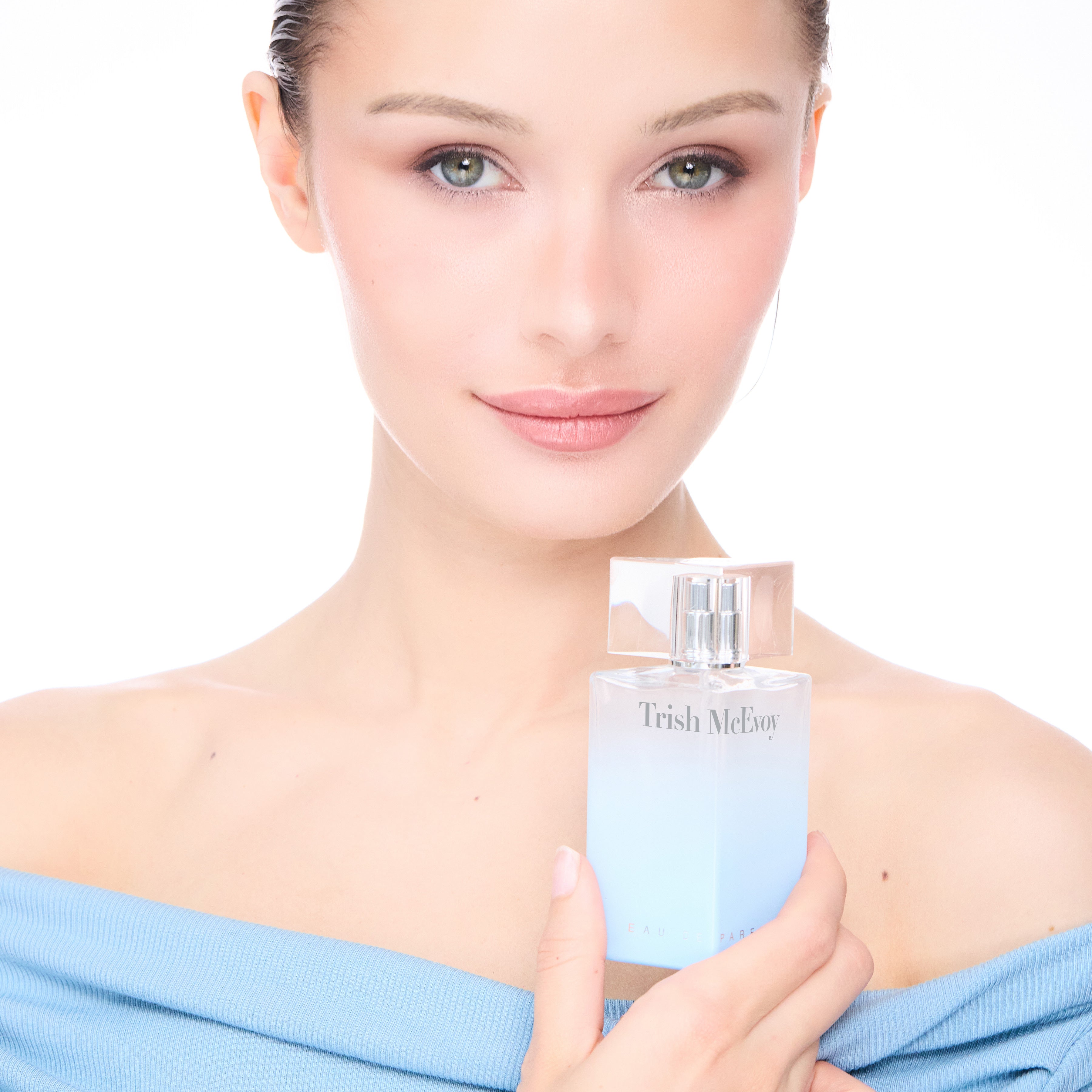 Woman holding a Trish McEvoy perfume bottle against a white background
