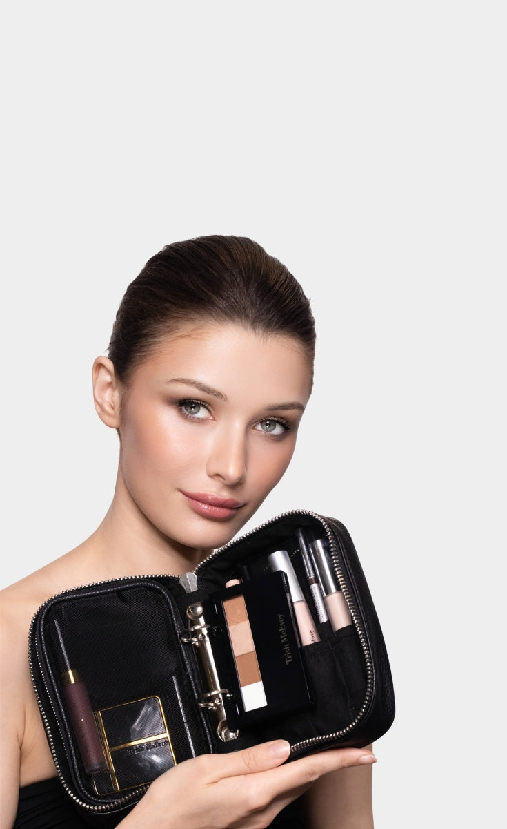 Woman holding a makeup case with cosmetic products on a plain background