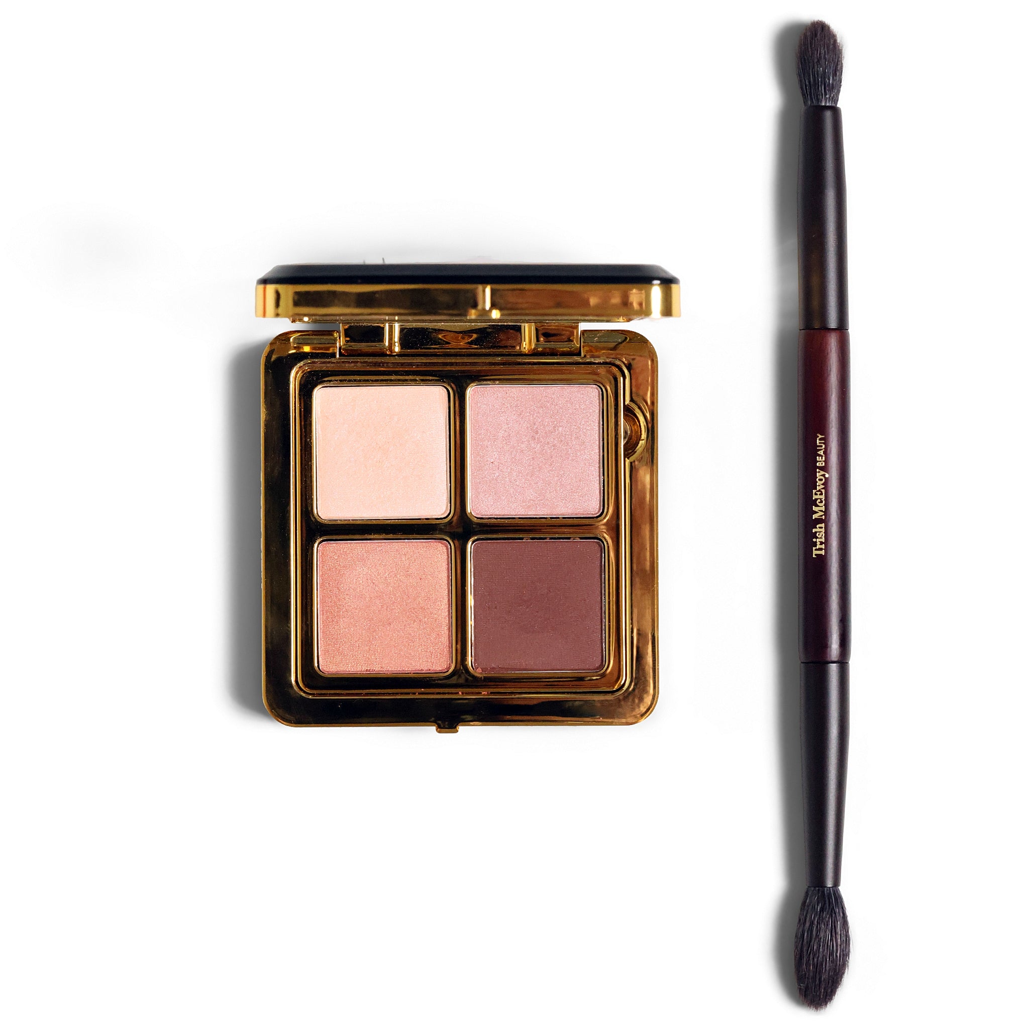 A four-shade eyeshadow palette in a gold compact next to a dual-ended makeup brush on a white background. The shades include light pink, shimmery pale pink, dusty rose, and mauve-brown.