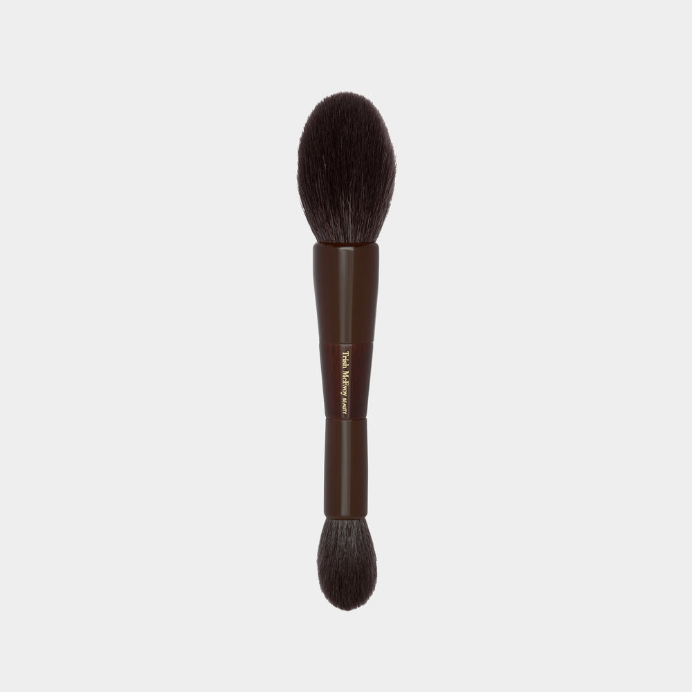 Makeup brush with brown handle and bristles on a light gray background
