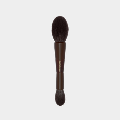 Makeup brush with brown handle and bristles on a light gray background