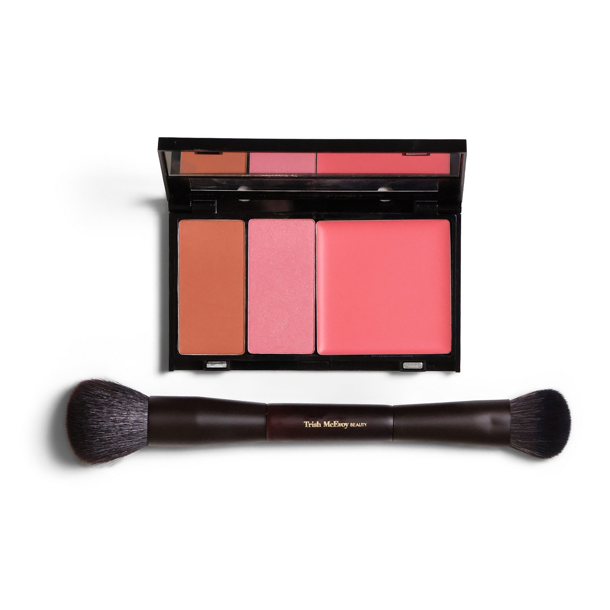 A makeup palette with three blush pans in warm peach, pink, and coral shades in a black compact, shown above a dual-ended makeup brush with a dark brown handle and black bristles. The compact is open, revealing the blush colors.