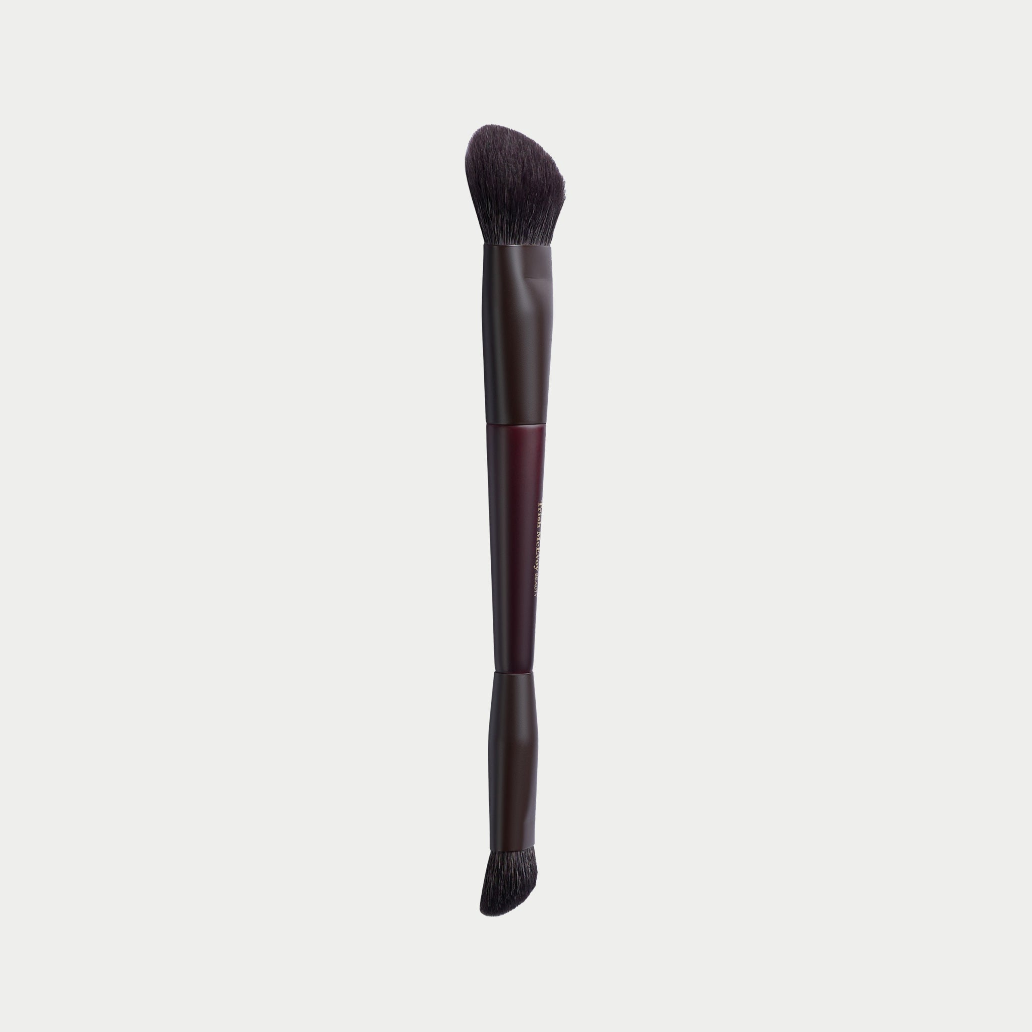 A makeup brush with dark brown bristles, a dark brown handle, and a metallic burgundy ferrule, shown vertically against a light gray background.