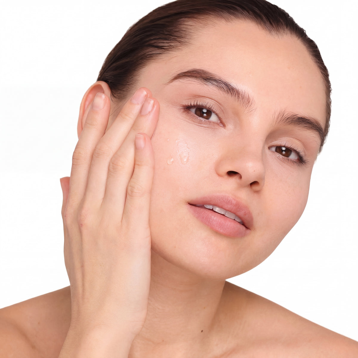 Woman applying a skincare product to her face on a white background