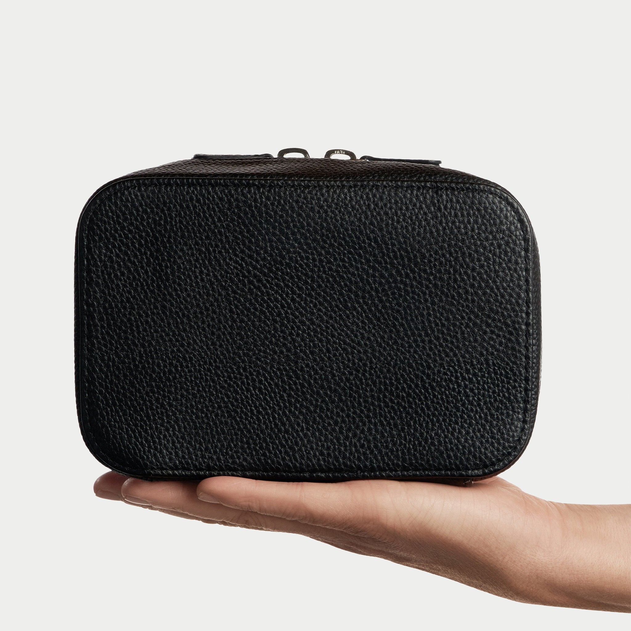 Black leather travel case with zipper on a light gray background