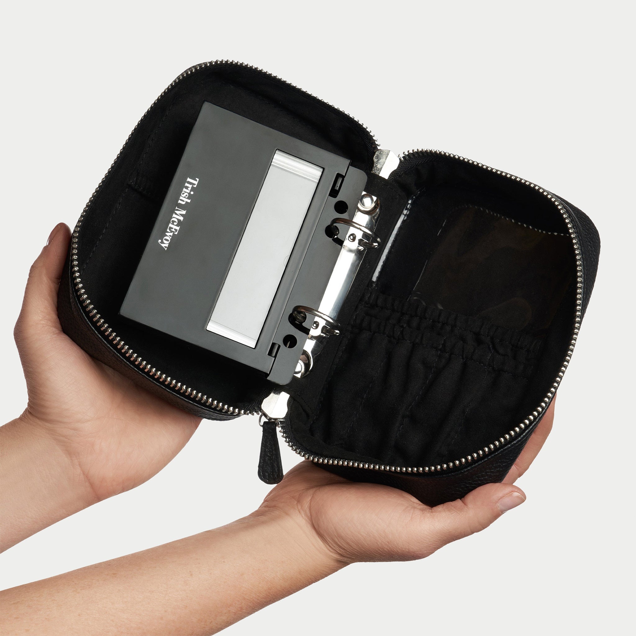 Black leather travel case with zipper on a light gray background