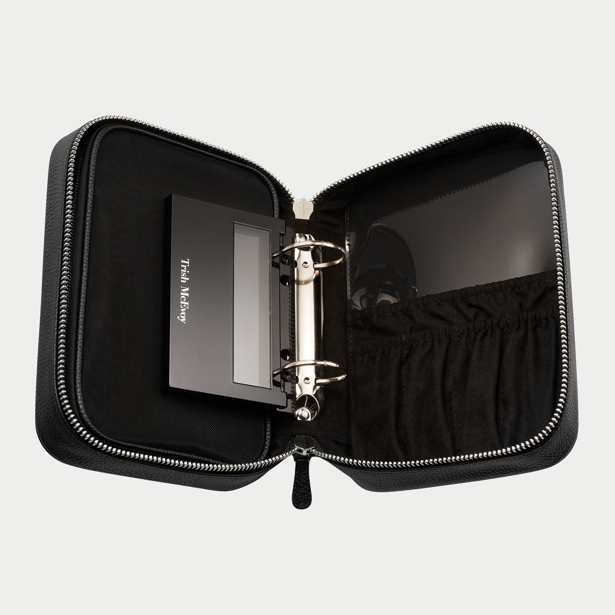 Black zippered case with a ring binder inside on a light gray background