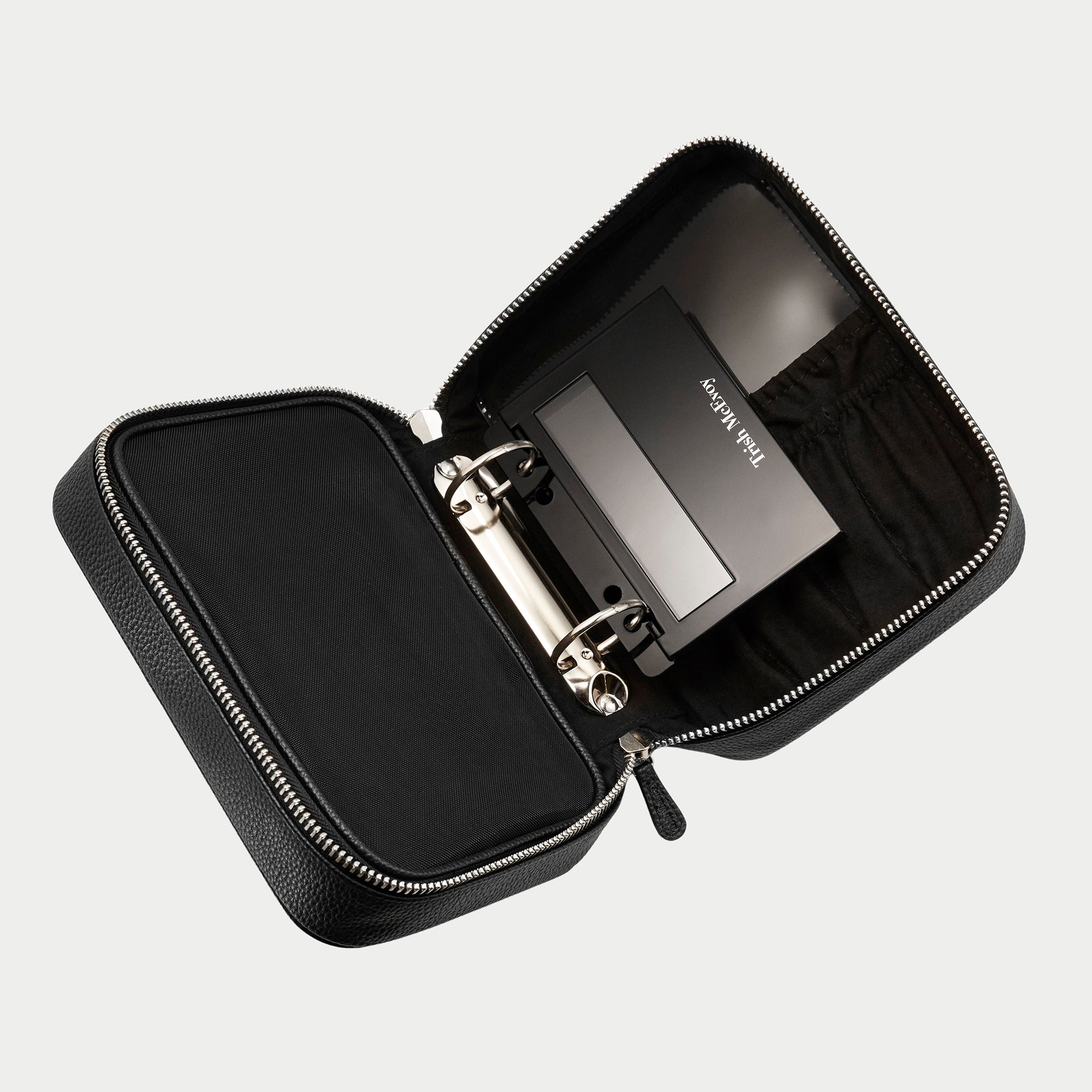 Black travel case with a silver device inside on a light gray background