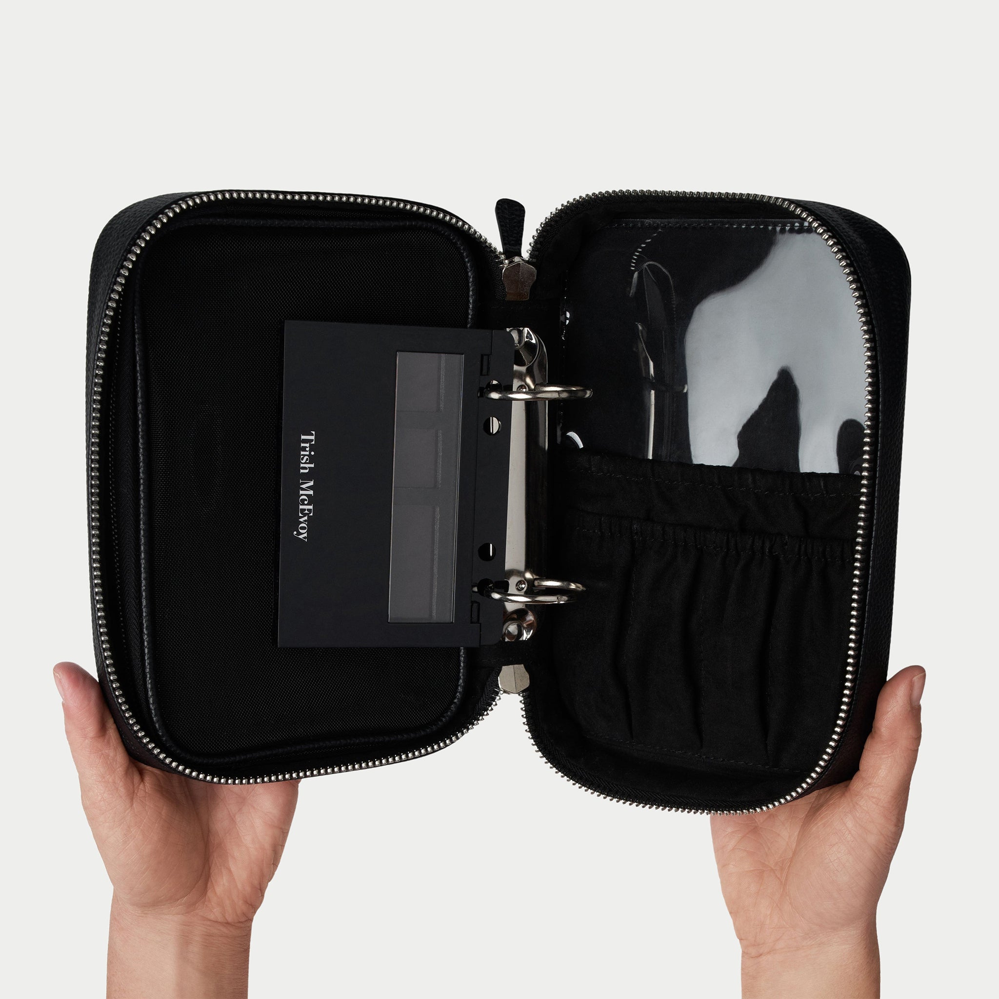 Black travel case with a mirror and other items on a light gray background