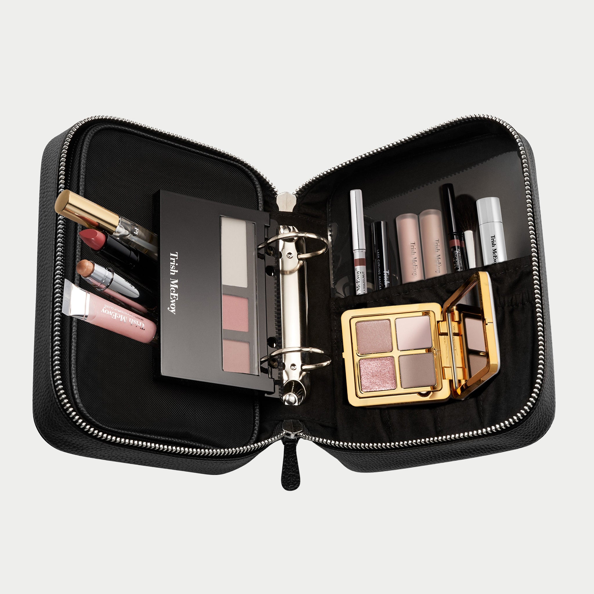 Makeup set with various products in a black travel case on a light gray background
