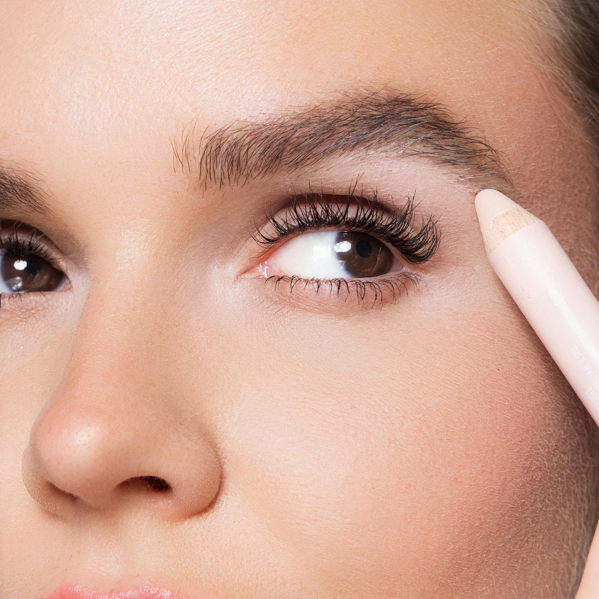 Close-up of a person applying eye brightening pencil. 