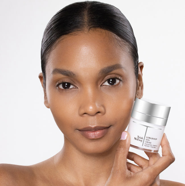 Woman holding a skincare product with a plain background