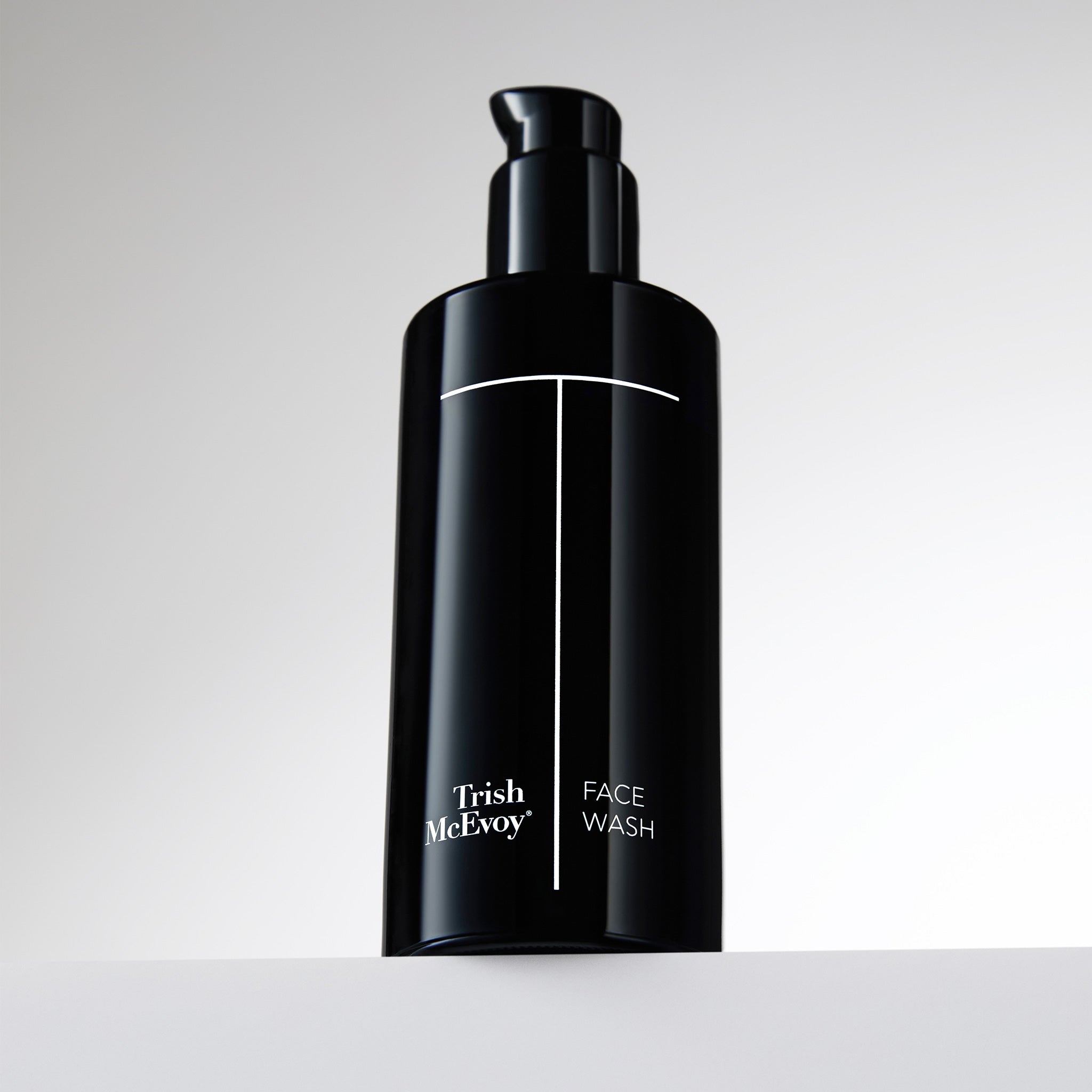 Black bottle of Trish McEvoy Face Wash on a light gray background