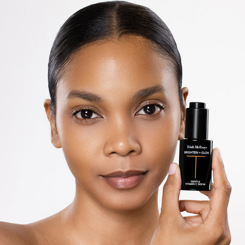 Woman holding a Trish McEvoy skincare bottle against a white background
