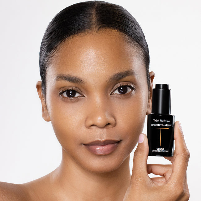 Woman holding a Trish McEvoy skincare bottle against a white background