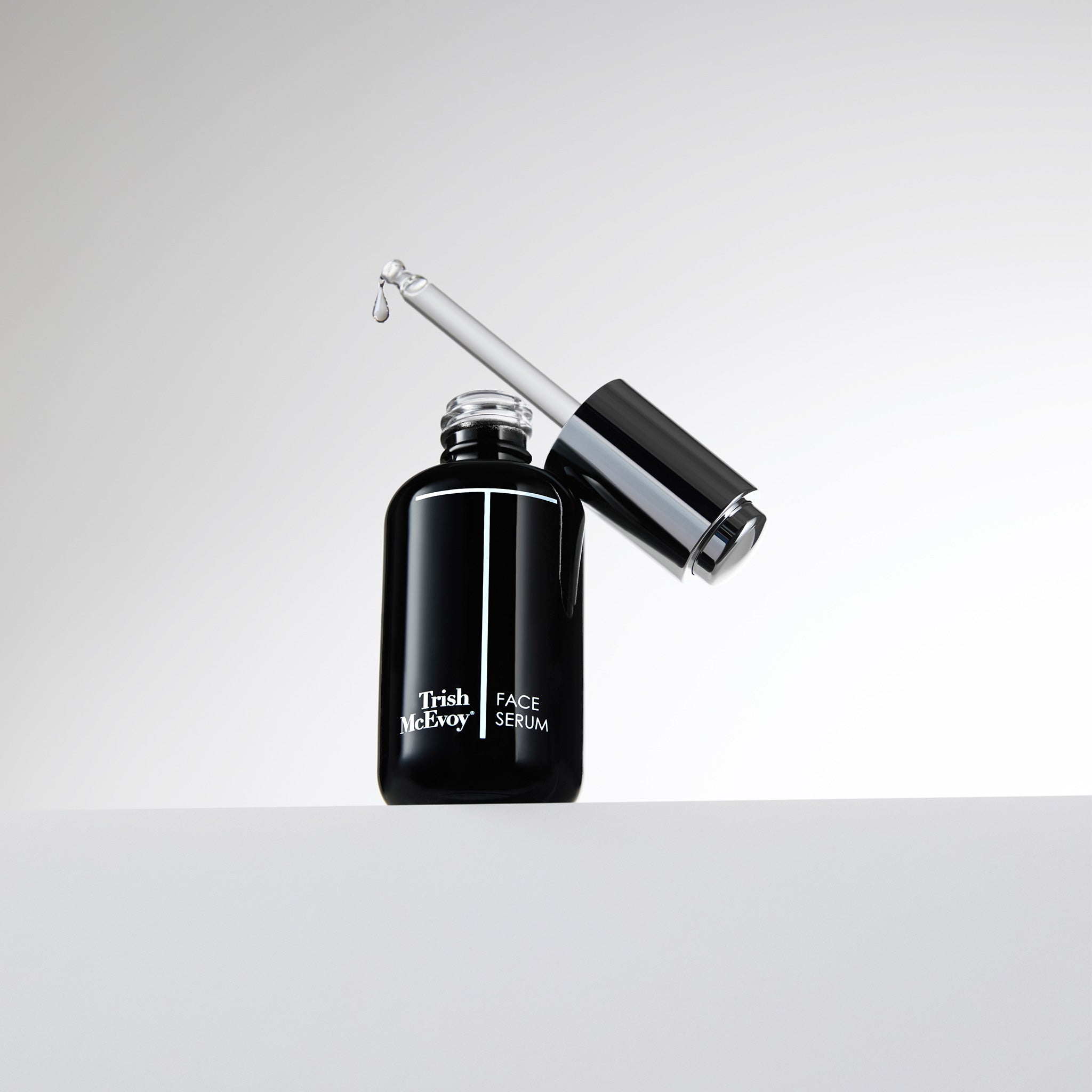 Black face serum bottle with dropper on a white background