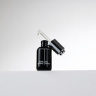 Black eye serum bottle with dropper on a white background