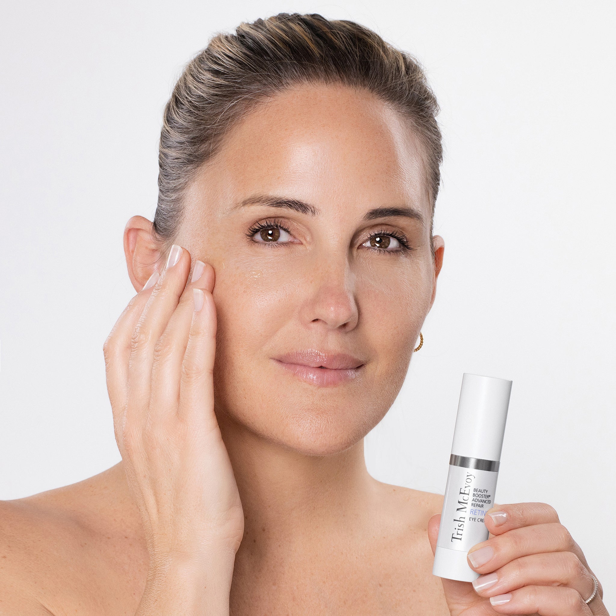 Woman holding a skincare product with a plain background