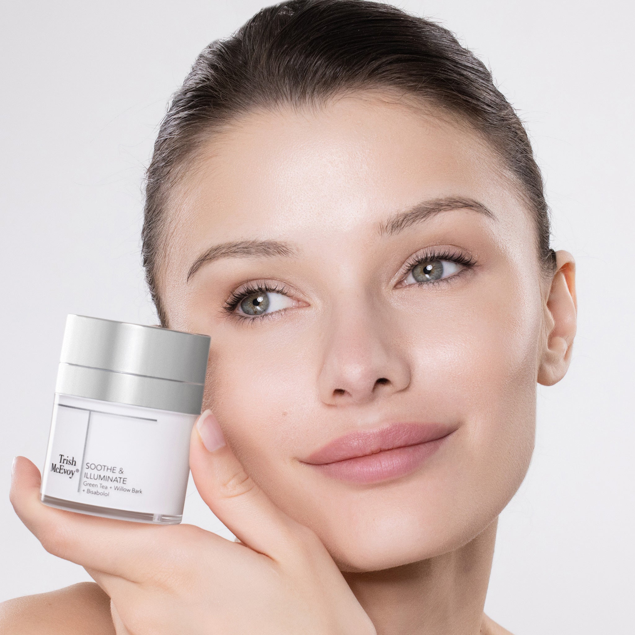 Woman holding a skincare product with a plain background