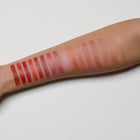 Multiple rows of lip swatches on a person's arm