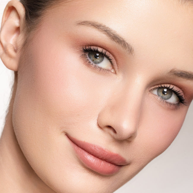 Close-up of a woman's face with color pink glow blush