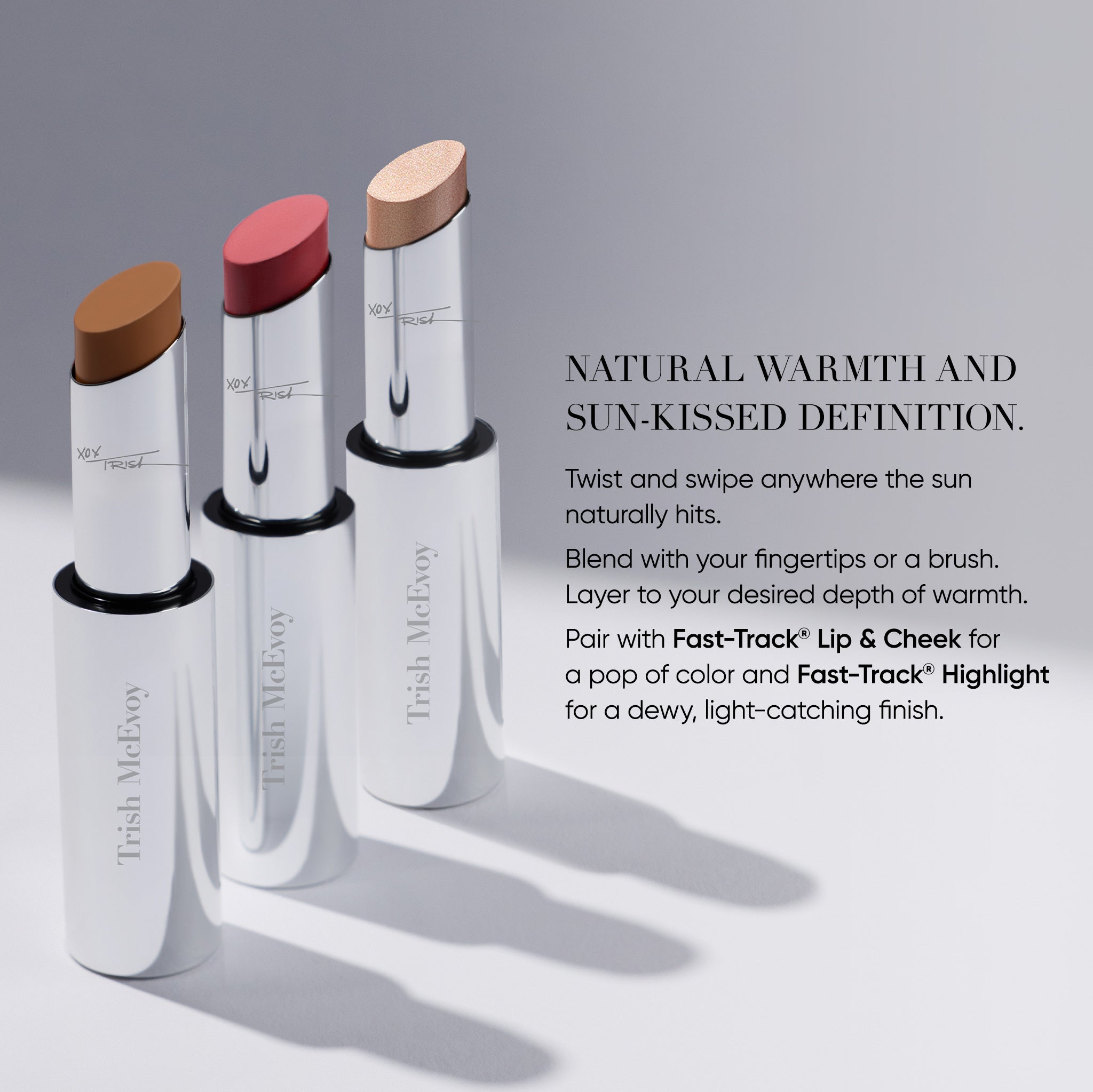 Three Trish McEvoy lipsticks in silver tubes standing upright on a light gray background, with one brown bullet, one pink bullet, and one beige bullet exposed. Text on the right describes the natural warmth and sun-kissed definition of the shades.