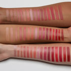 Multiple rows of lip swatches on a person's arm with various shades of pink, red, and brown.