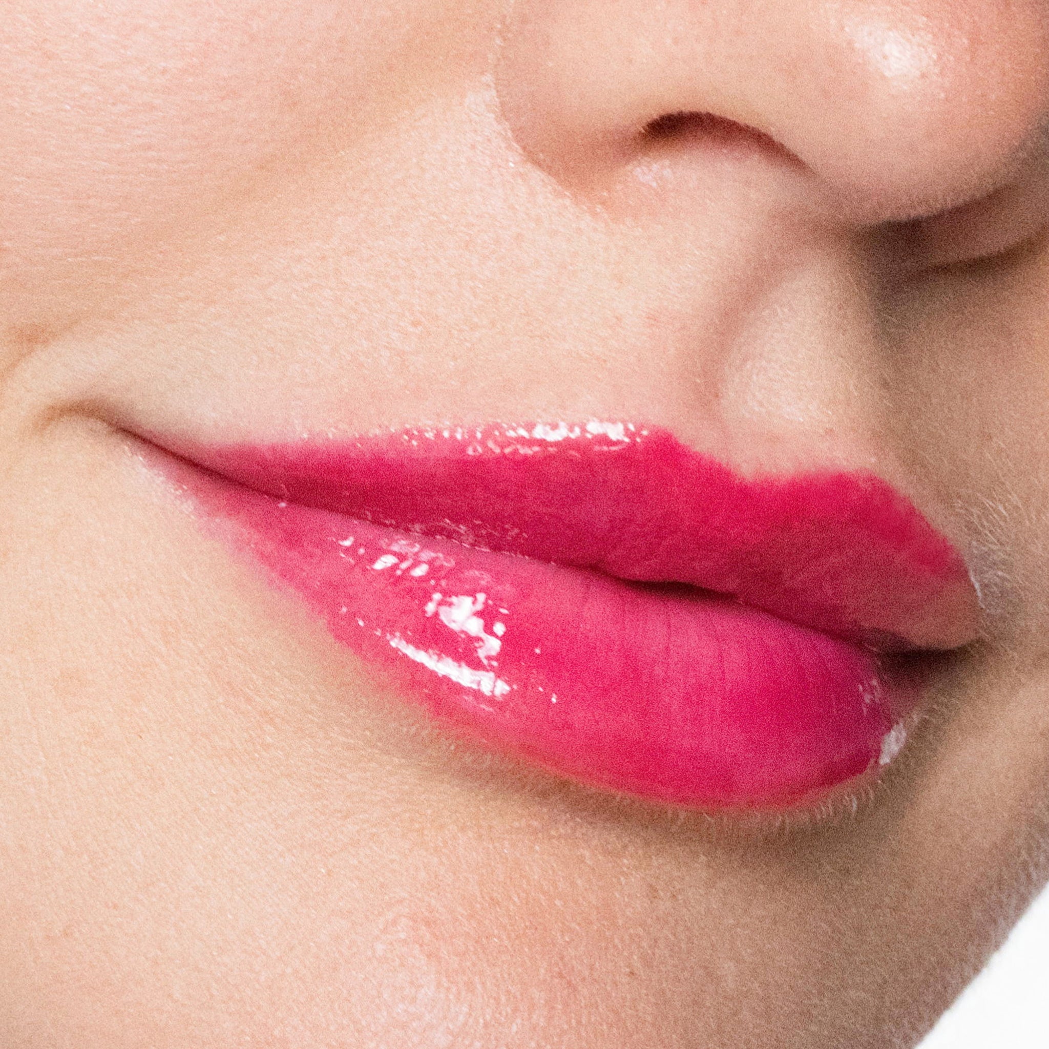 Close-up of a person's lips with color gorgeous lipgloss on a neutral background