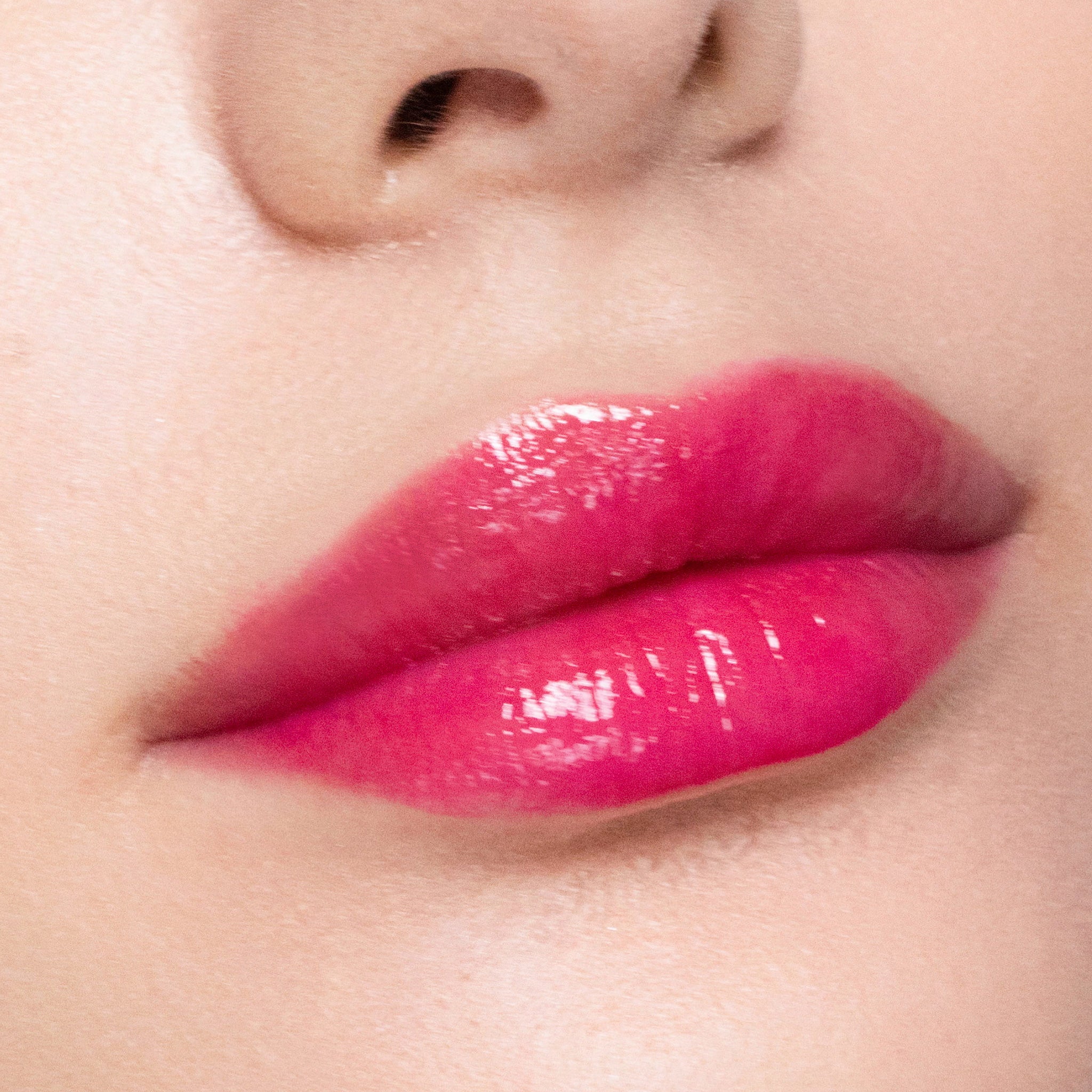 Close-up of a person's lips with color gorgeous lipgloss on a neutral background