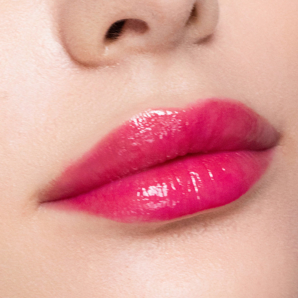Close-up of a person's lips with color gorgeous lipgloss on a neutral background