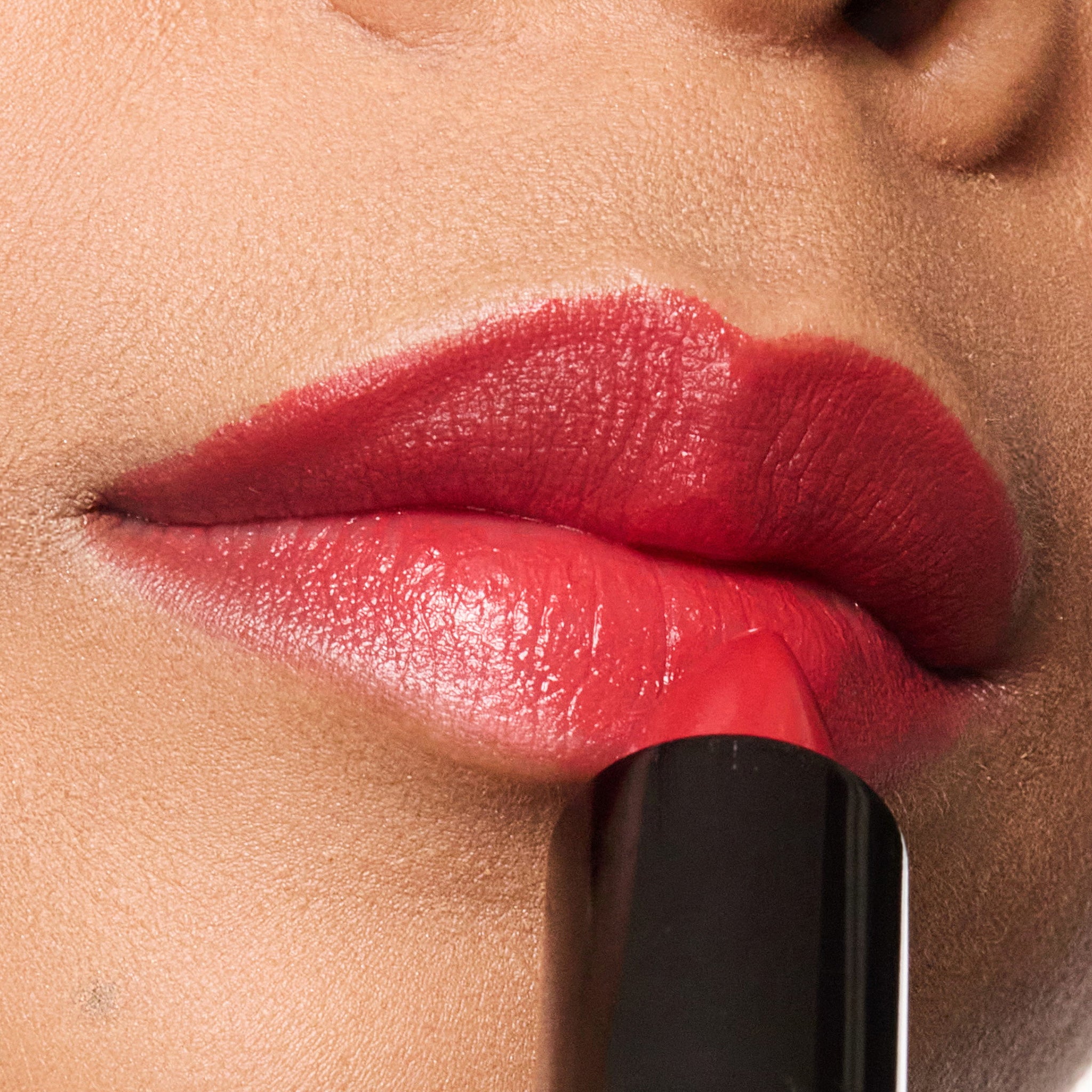 Close-up of a woman applying color rendezvous lipstick to her lips.