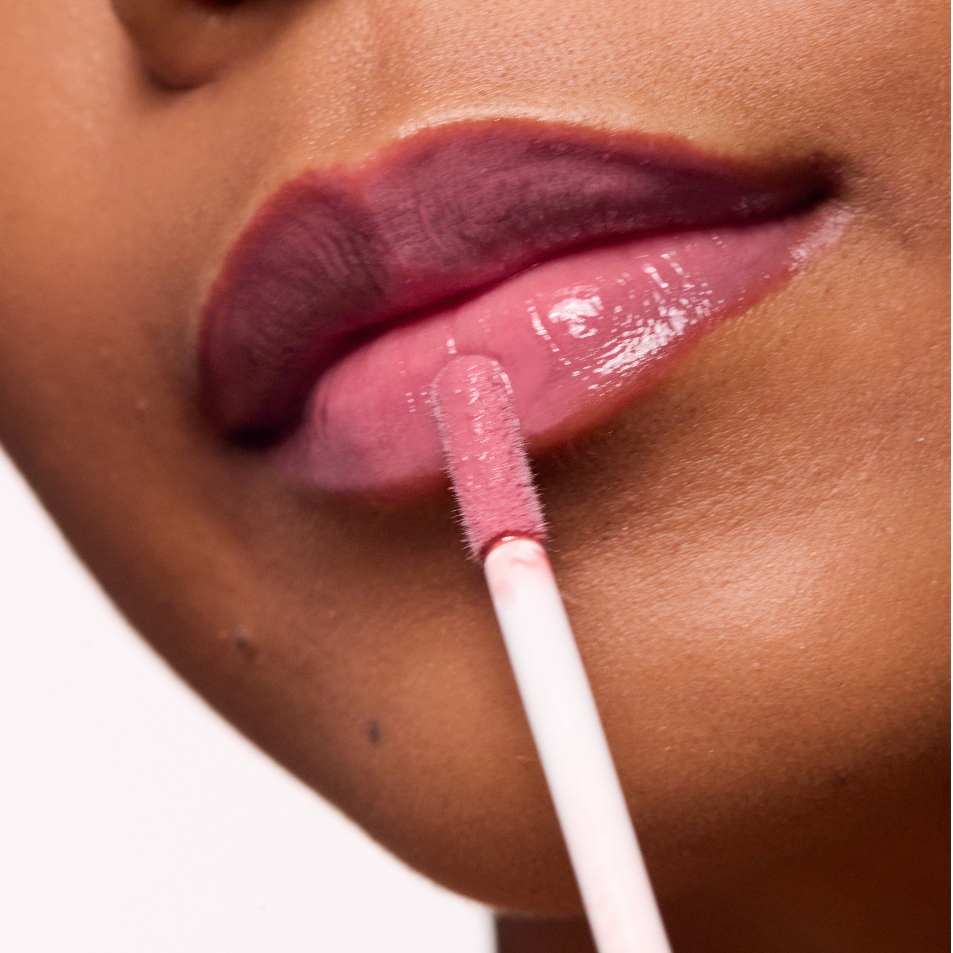 Close-up of a person applying Color timeless lip gloss with a applicator.