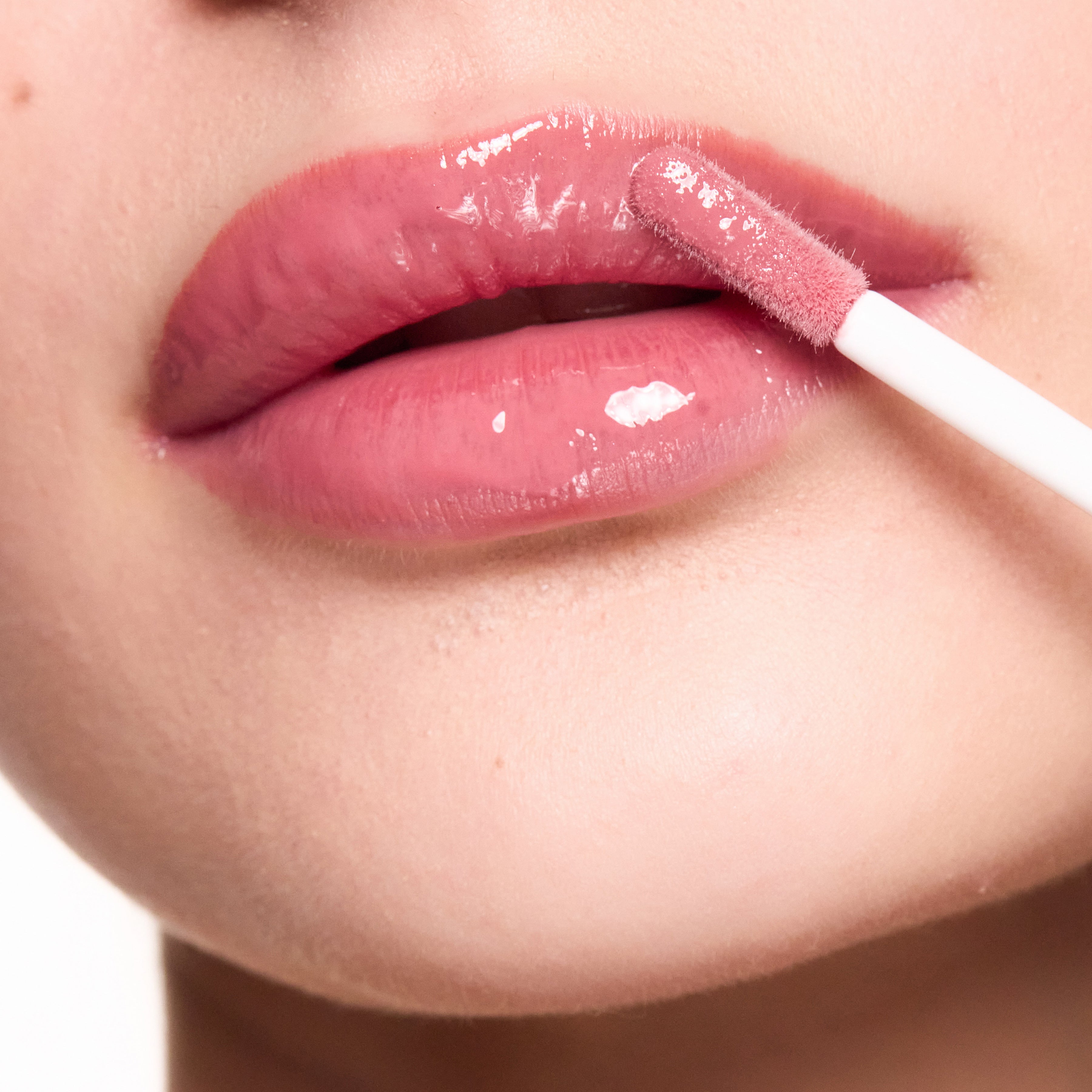 Close-up of a person applying Color timeless lip gloss with a applicator.