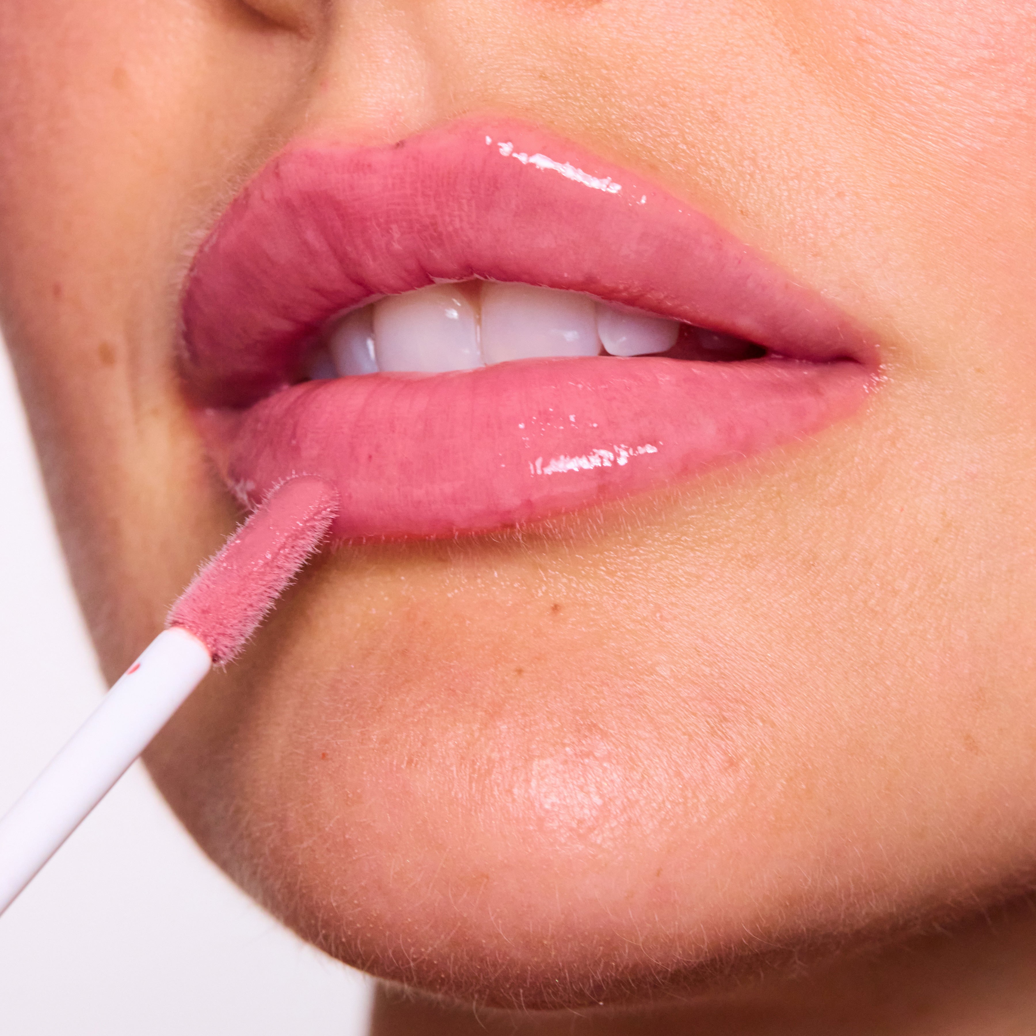 Close-up of a person applying Color timeless lip gloss with a applicator.
