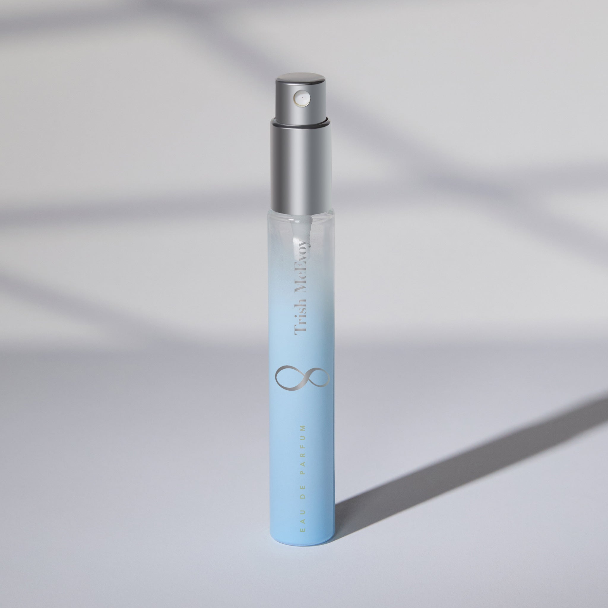Small blue spray bottle with silver cap on a light gray background