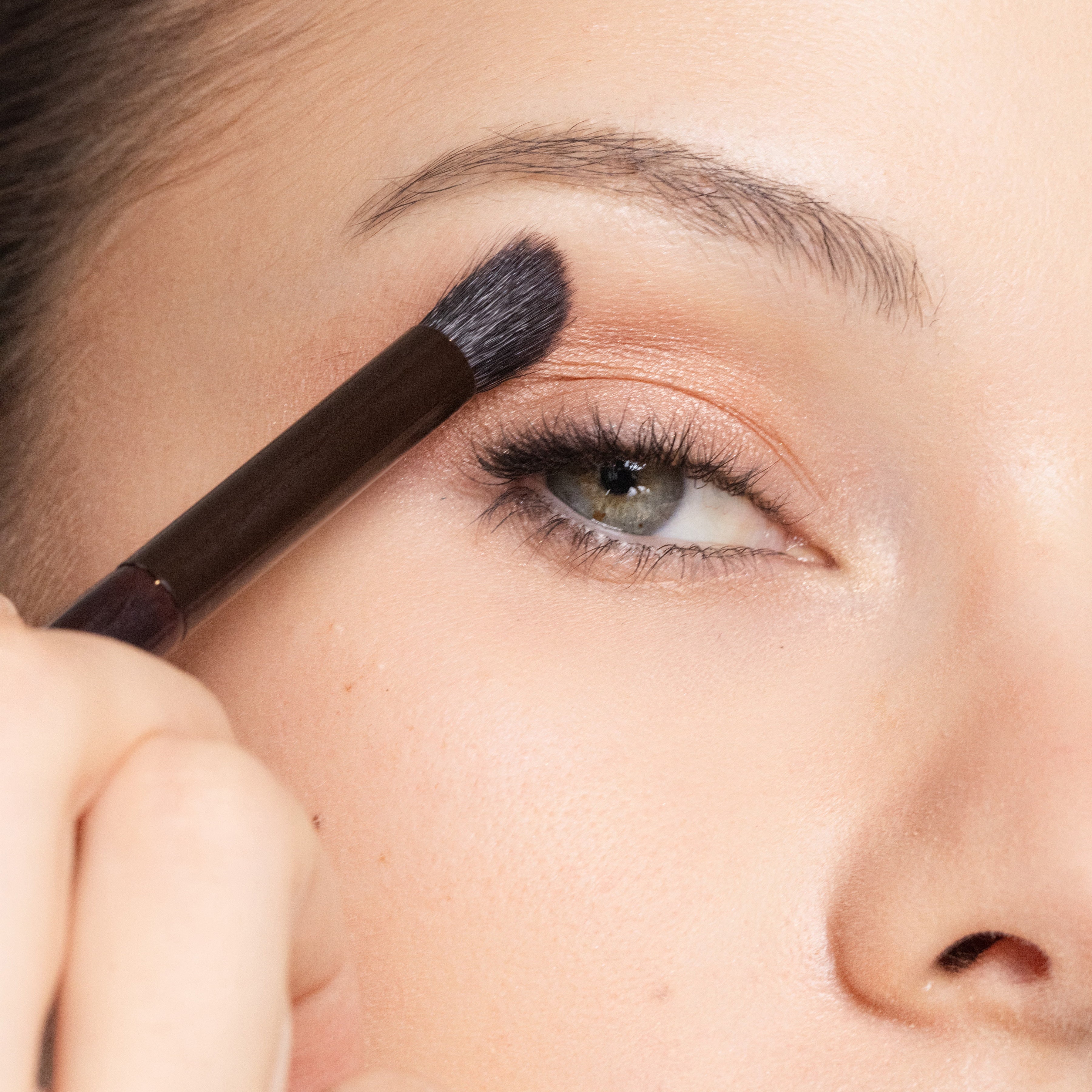 Close-up of a person applying makeup with Brush 23 Place + Define to their eyebrow.