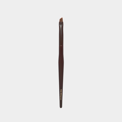 Makeup brush with brown handle and black bristle head on a light gray background