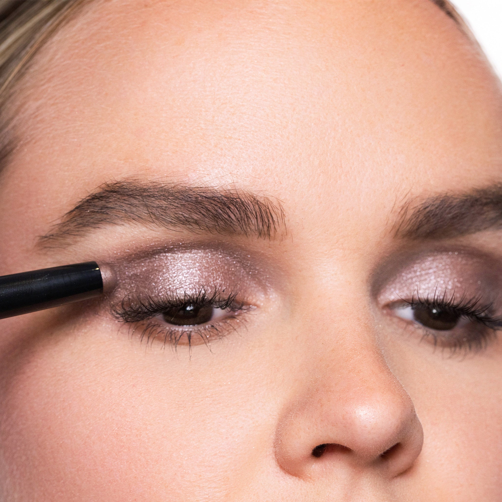 Close-up of a person applying smoky quartz eye makeup