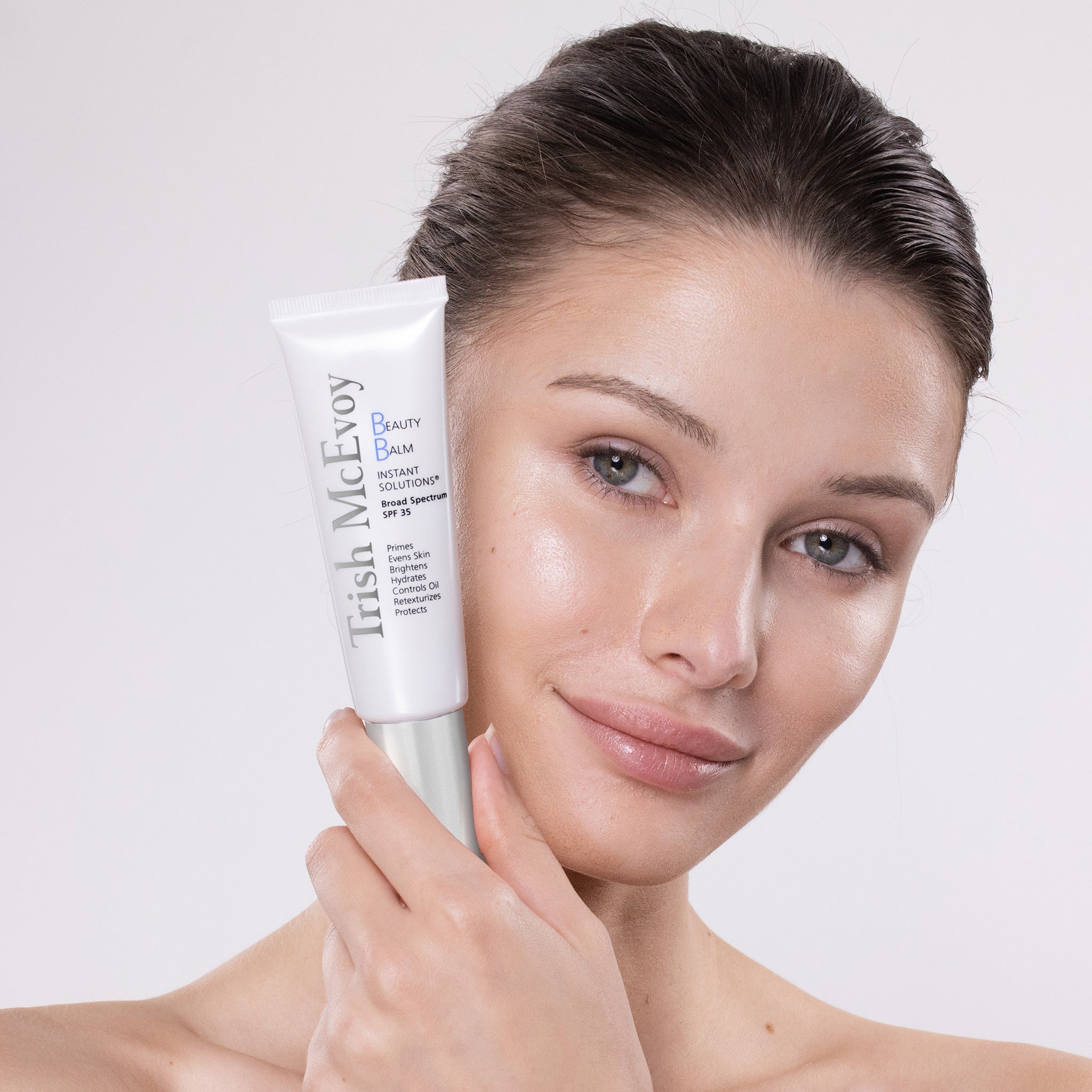 Woman holding a tube of Irish McEvoy Beauty Balm against a plain background