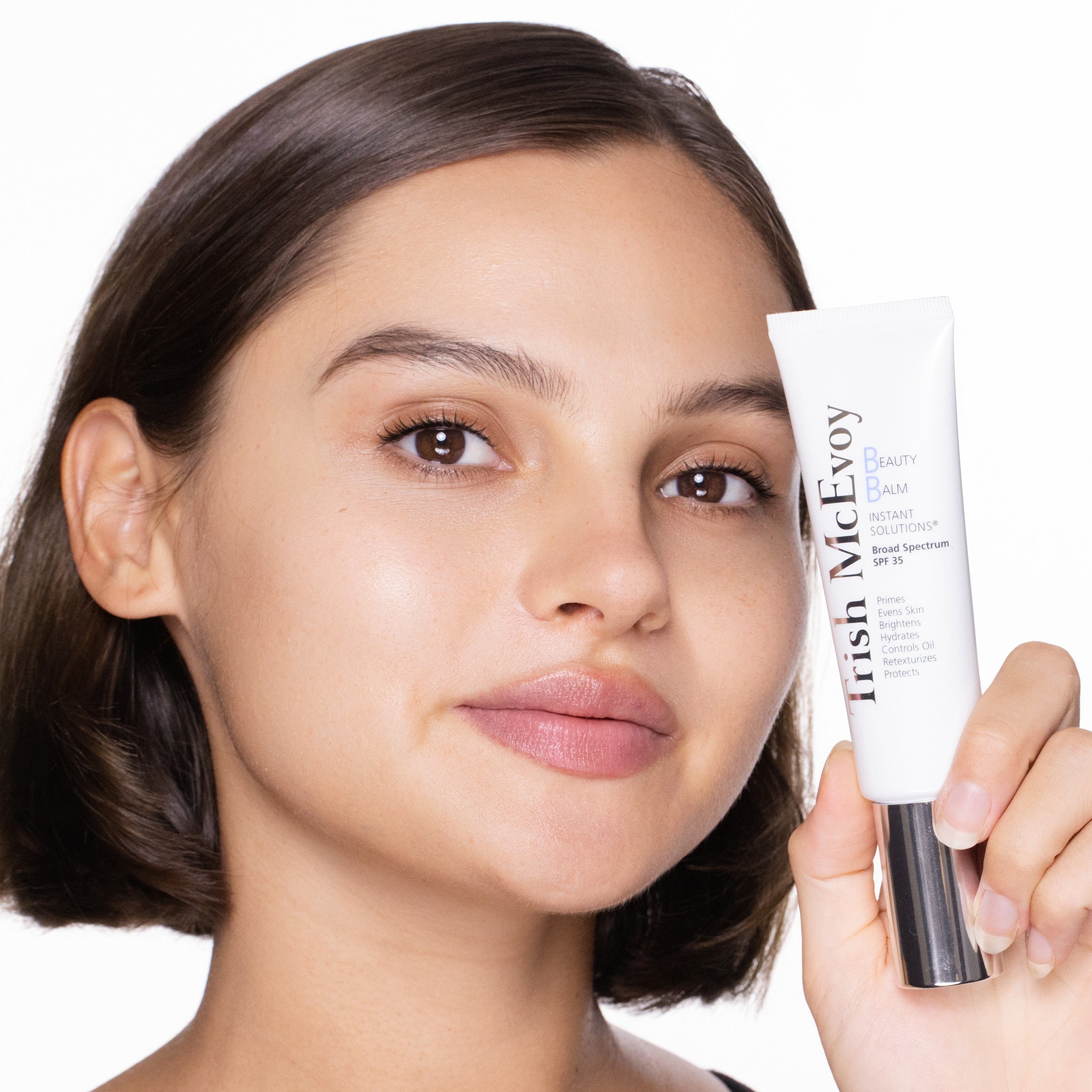Woman holding a skincare product with a neutral background