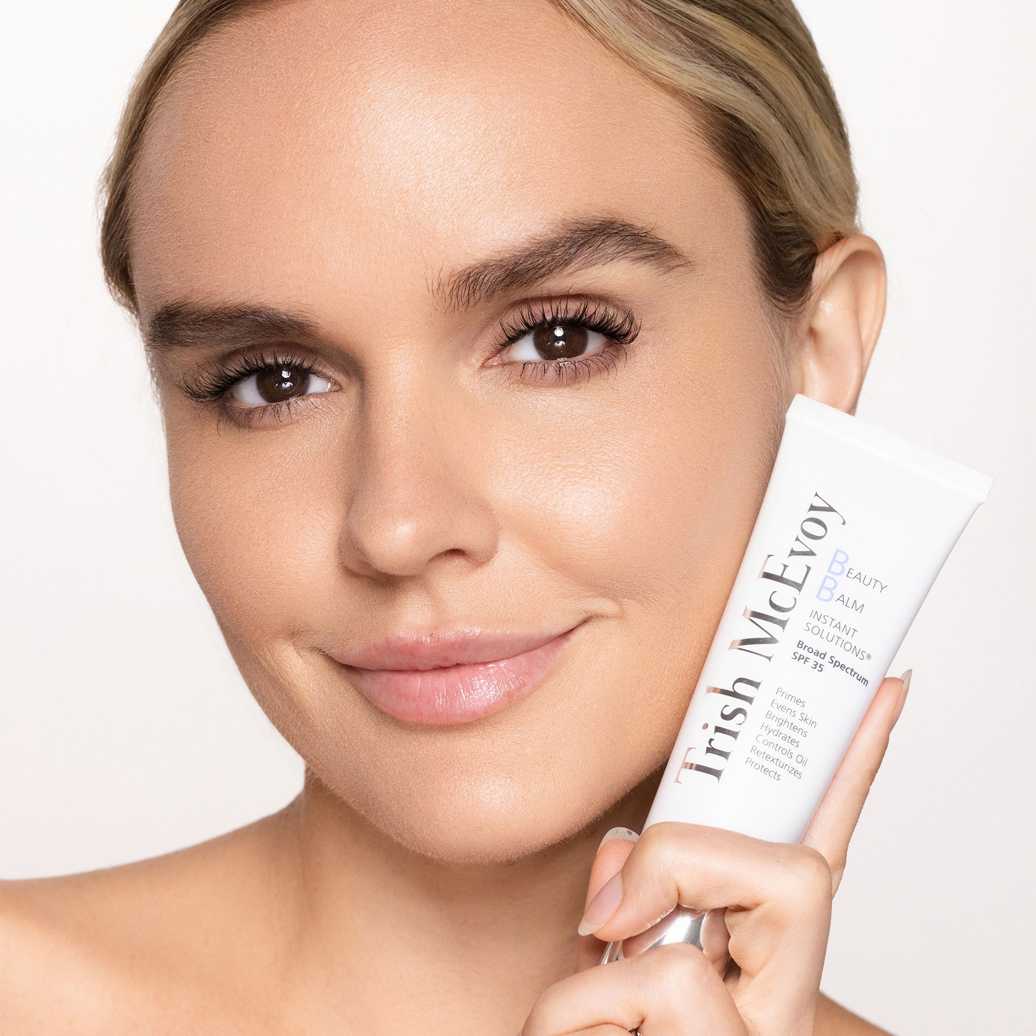 Woman holding a skincare product with a neutral background