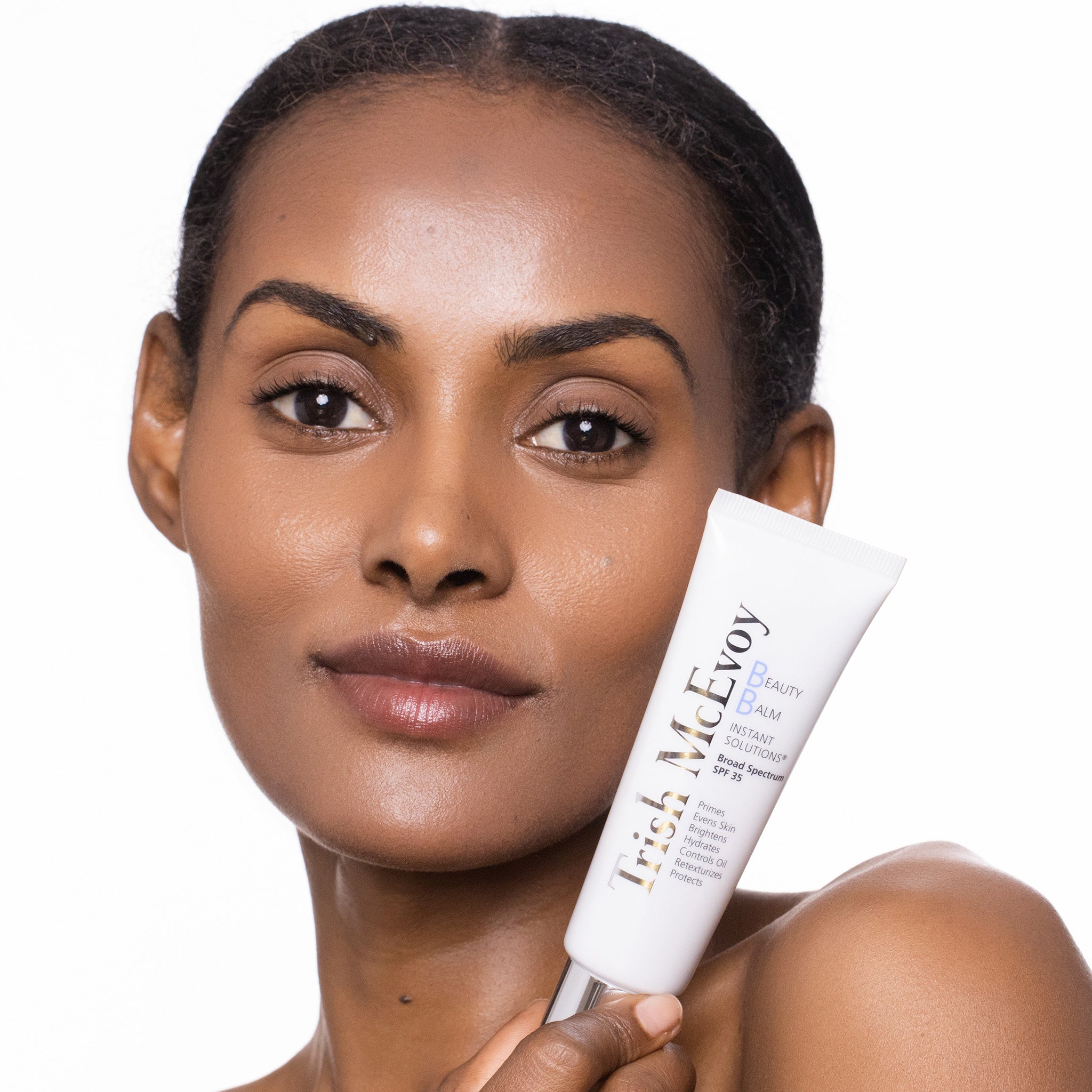 Woman holding a tube of Irish McEvoy skincare product on a white background